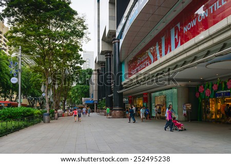 SINGAPORE - 01 JAN 2014: Pedestrians walk along famous Orchard road near entrance to a big shopping mall with sale poster. Orchard Road is the most popular shopping area of Singapore
