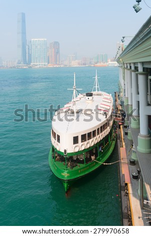 HONG KONG, CHINA - 18 JAN 2015: Star Ferry, an important source of public transportation, tied to the central pier in Kowloon, awaiting passengers, with the Hong Kong skyline in the background.