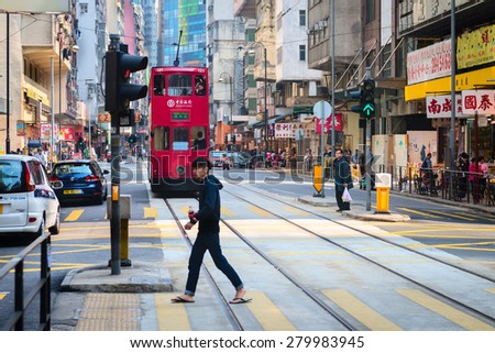 HONG KONG, CHINA - 18 JAN 2015: Pedestrian crossing a typical, busy street in central Hong Kong, China.