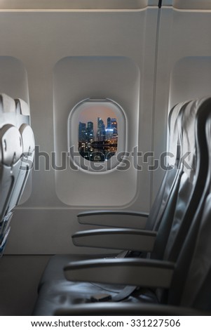 View from a commercial aircraft showing the beautiful cityscape at night through the cabin window and the comfortable chairs