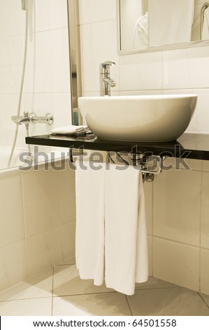 Bathroom fixtures with white washstand and faucet with towels