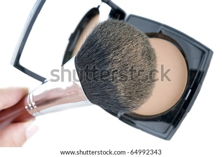 Make-up brush on powder-case with mirror. Selective focus on the brush top
