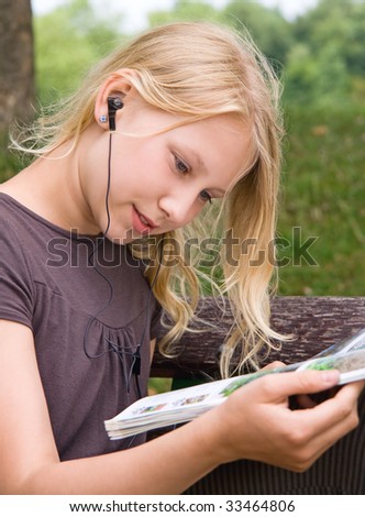 A Girl is reading a magazine while listening to music