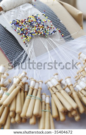 Close-up of special lace making pin cushion. Pins and wooden bobbins for lace making. Traditional craft in many countries in Europe