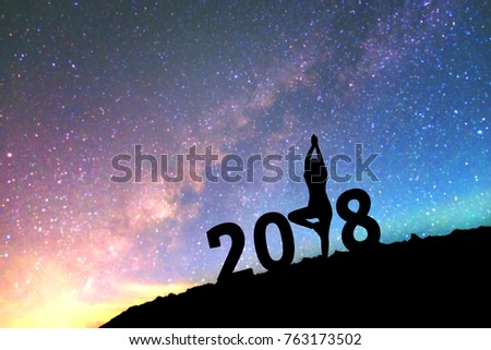 Silhouette young woman practicing yoga on 2018 new year on  the Milky Way galaxy pointing on a bright star. dark sky tone . Vintage grain tone.