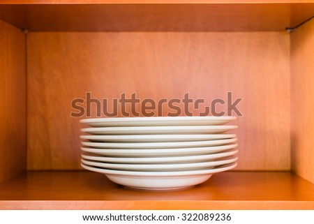 Decluttered minimalistic kitchen cabinet for simple living. Contains one single type of plates: white porcelain pasta or soup bowl plates.