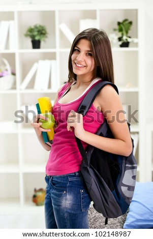 Young student girl ready for school, holding books and book bag