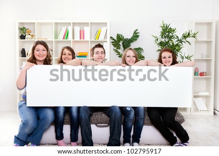 Group of  young smiling teenager holding blank banner in front of them