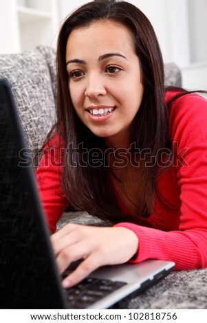 Young girl lying on couch and surfing on net
