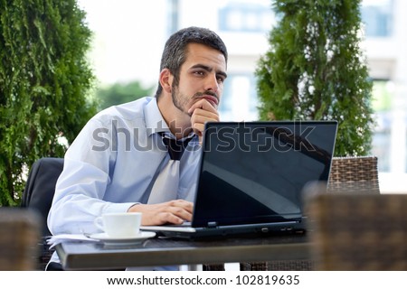 Business man in deep thought with laptop and documents on table