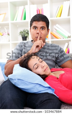 Young beautiful woman  sleeping , man holding finger to lips as a sign of silence, making silence for his girlfriend