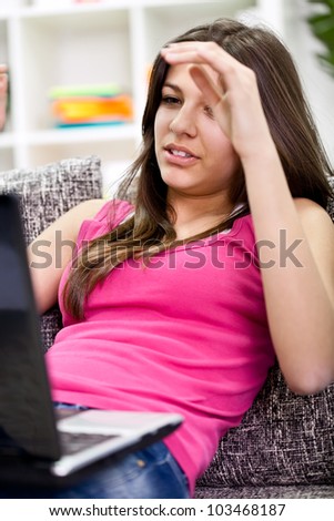 Upset young student sitting on couch studying on a laptop, isolated on white