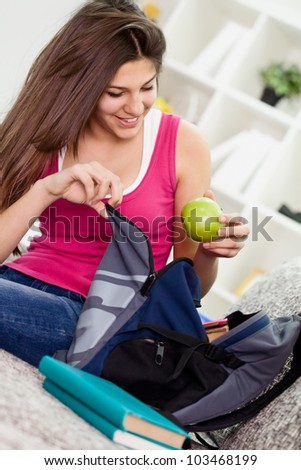 Teen girl  packing book bag preparing for school.