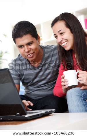 Young people sitting on couch and using laptop at home