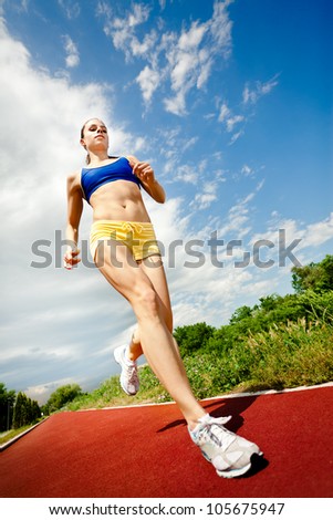 Running woman. Female runner in front of blue sky, low angle.outdoors training for marathon run.