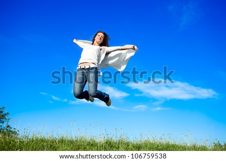 Woman jumping with a white scarf on the meadow