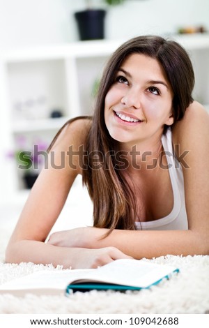 Close up portrait of teen girl lying on the floor and reading book