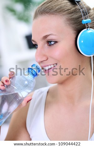 Fitness girl drinking water with headphones