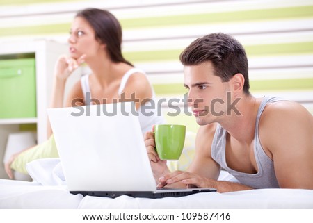 disappointed woman because he does not pay attention to her, he looking in laptop