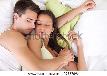 Portrait of lovely young couple sleeping together on bed