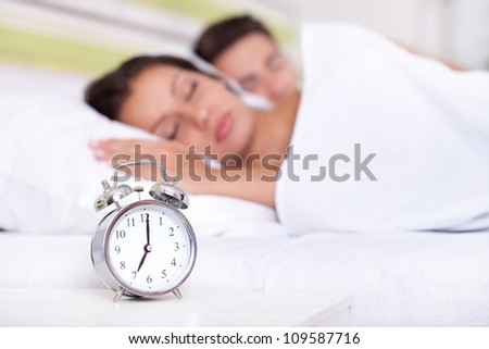 Young couple sleeping together in bed with  alarm clock