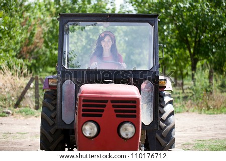 Young cute woman driving tractor