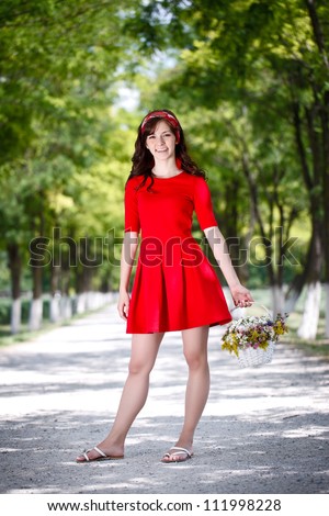 Beautiful country girl posing in red dress with flowers basket