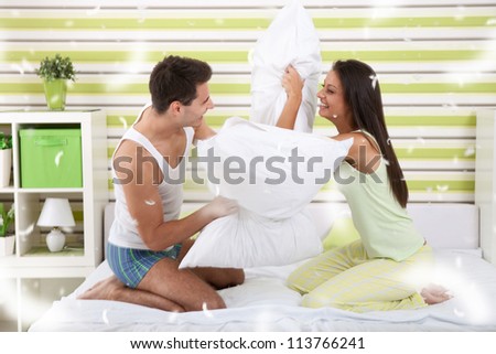 Portrait of sexy young couple having pillow fight in bedroom