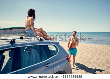 Healthy Active Lifestyle. Surfing. Summer Vacation. Extreme Sport. Smiling surfer girl sitting on the car and getting ready for surfing