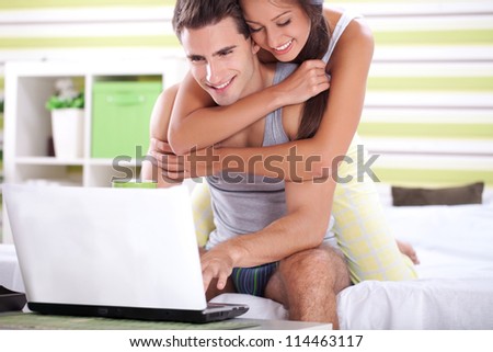 Couple in bedroom in pajamas with laptop surfing together on net