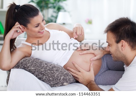 Future father holding hands on stomach his wife and feeling the baby move