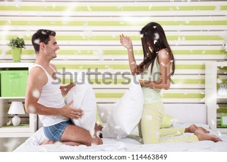 happy couple fighting with pillows in bed