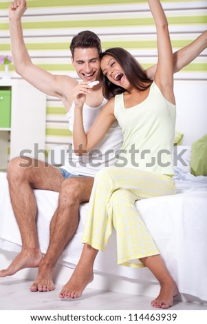 young happy couple with pregnancy test in bedroom