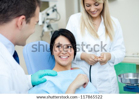 Male dentist, his assistant and female patient in dental practice