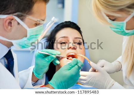 female patient with open mouth receives an injection at the dentist