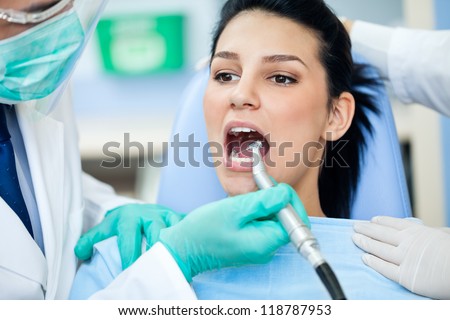 Female patient with open mouth during drilling  treatment at the dentist