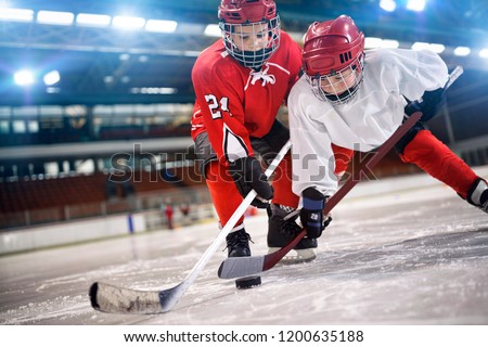 young children hockey player handling puck on ice