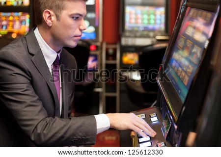 Young handsome men gambling in the casino on slot machines