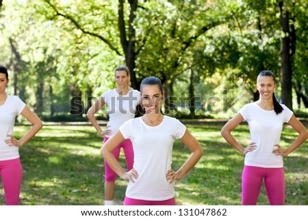 Group of sporty woman exercising in park, smiling and looking in camera