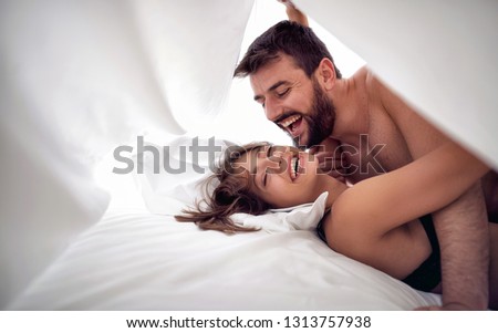 Smiling man and woman lovers having sex on a bed in morning
