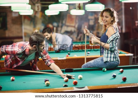 plays billiard and enjoying in beer-couple have funny time in bar