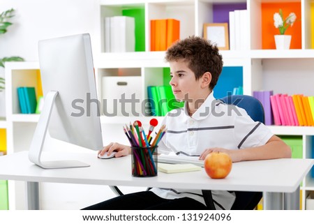 Concentrated young boy using computer in his room