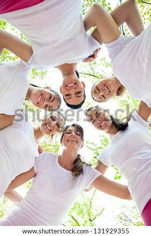 Six women standing with their heads in circle, smiling and looking at camera