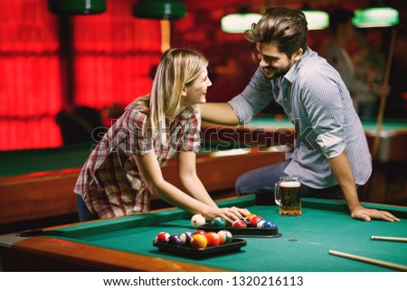 Young couple playing snooker together in pub