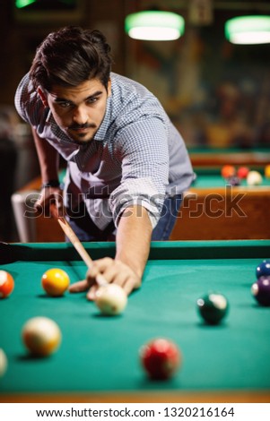 billiard game- young man playing snooker in club
