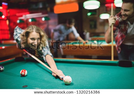 couple have funny time in billiard bar- woman playing snooker