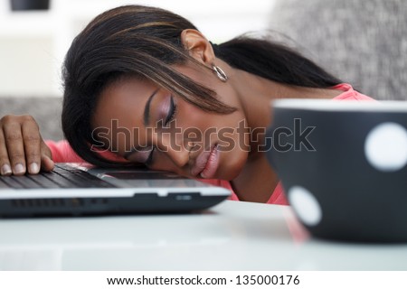 exhausted black young women sleeping with her head on a laptop computer