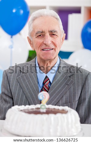 senior man having  birthday cake with a question mark candle