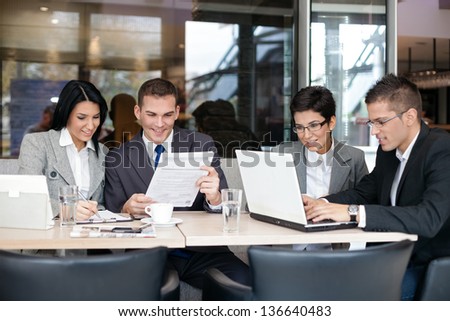 Group of young business people sitting at a table  and discussing an interesting idea in the cafe