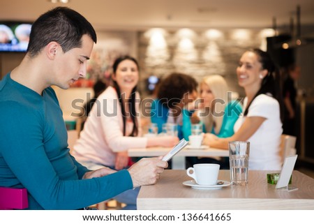 Group of girl watching handsome man in cafe, man ignoring girls